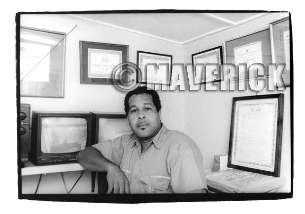 King (formerly Prince) Jammy, posing proudly in his studio office alongside a wall full of awards.